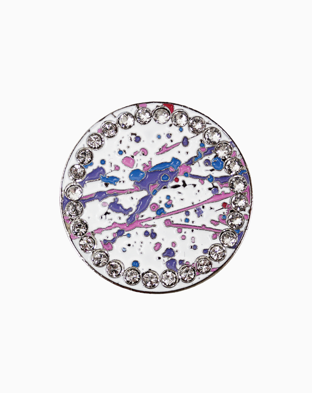 Round golf ball marker with a white enamel base and multicolour paint splatter design in blue, pink, and purple tones, surrounded by a ring of clear crystals for a polished, eye-catching finish.
