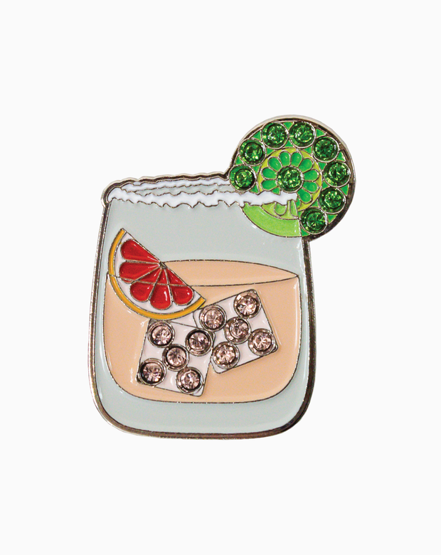 Golf ball marker shaped like a Paloma cocktail glass with grapefruit and lime details, accented with Swarovski crystals on a white background.
